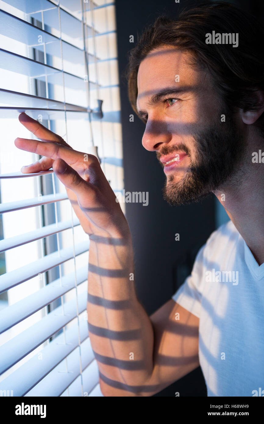 Mann, Blick durch Fenster-Vorhänge nach dem Aufwachen Stockfoto