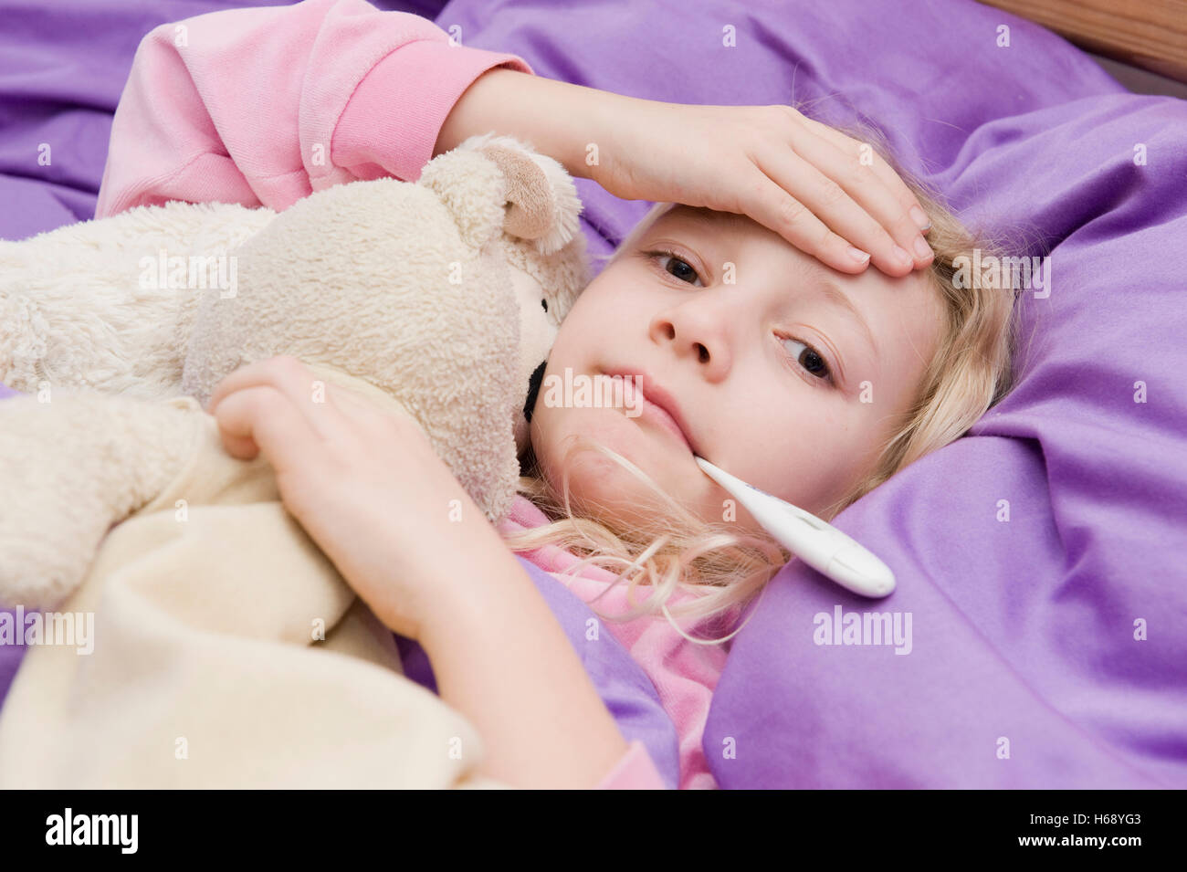 Krankes Mädchen mit Fieberthermometer im Bett Stockfoto