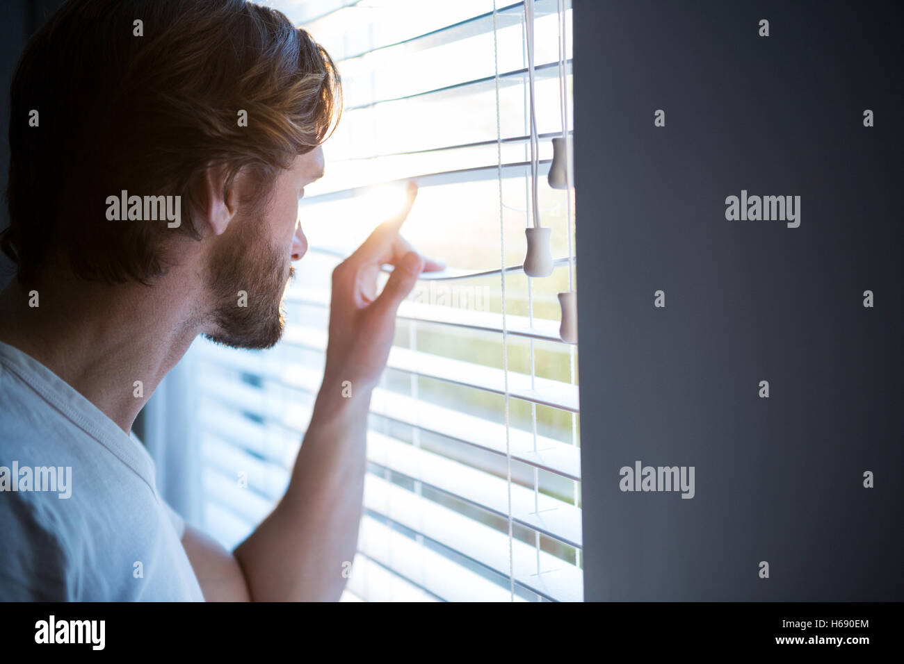 Mann, Blick durch Fenster-Vorhänge nach dem Aufwachen Stockfoto