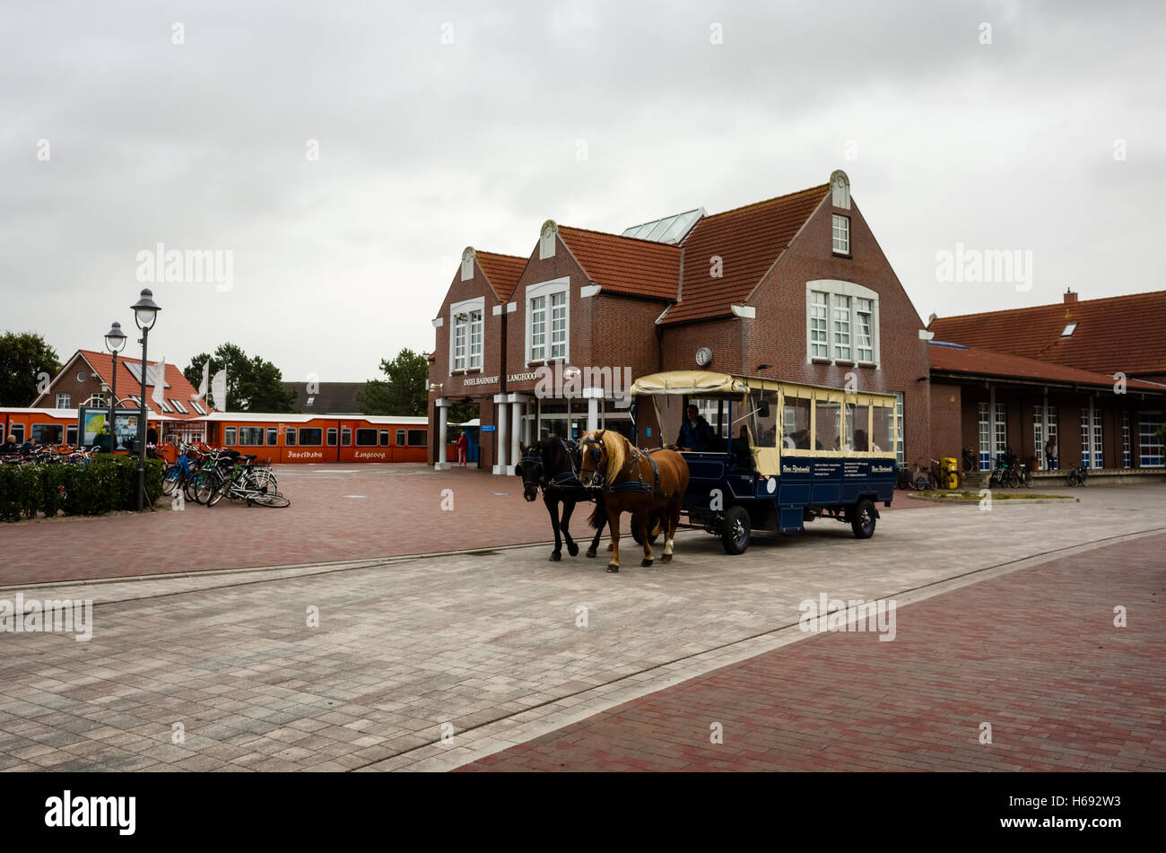 Inselbahnhof Langeoog. Deutschland Deutschland. Eine von Pferden gezogene taxi Beförderung ausserhalb Langeoog Bahnhof für die nächste Gruppe von Urlaubern auf der Insel ankommen, wartet. Es ist ein bewölkter Tag im Herbst. Stockfoto