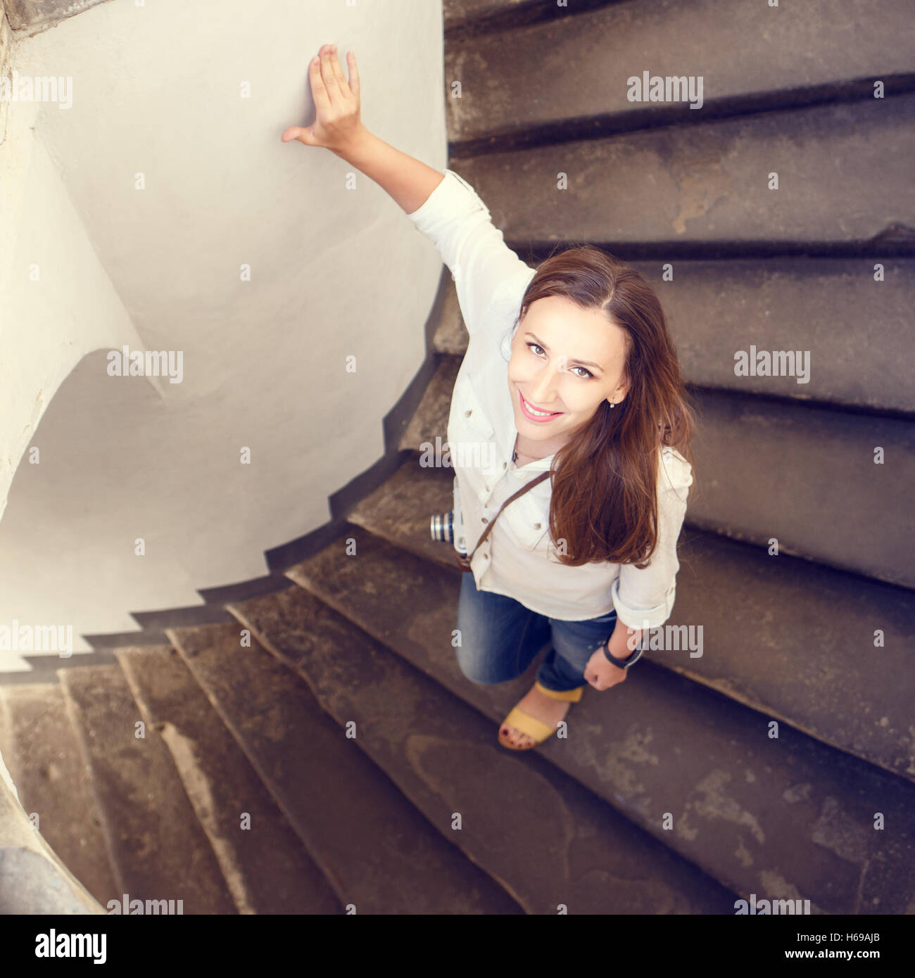 Junge lächelnde Frau schaute nach oben und Step-down an geschwungene Treppe Stockfoto