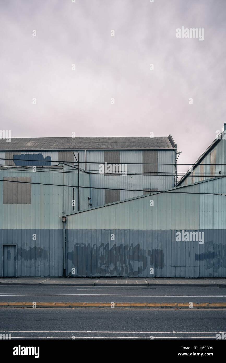 Altes Lagerhaus bemalt blau und grau mit gereinigten Graffiti und überdachte und schöne Türen an einem flachen, bewölkten Tag Stockfoto