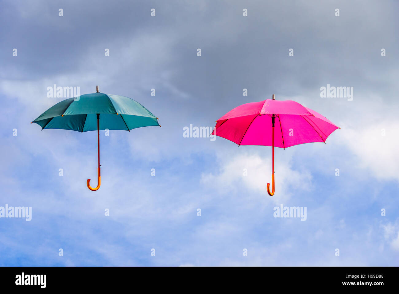 Rosa und grün Regenschirm oder Sonnenschirme schweben in der Luft schweben unter bewölktem Himmel Stockfoto