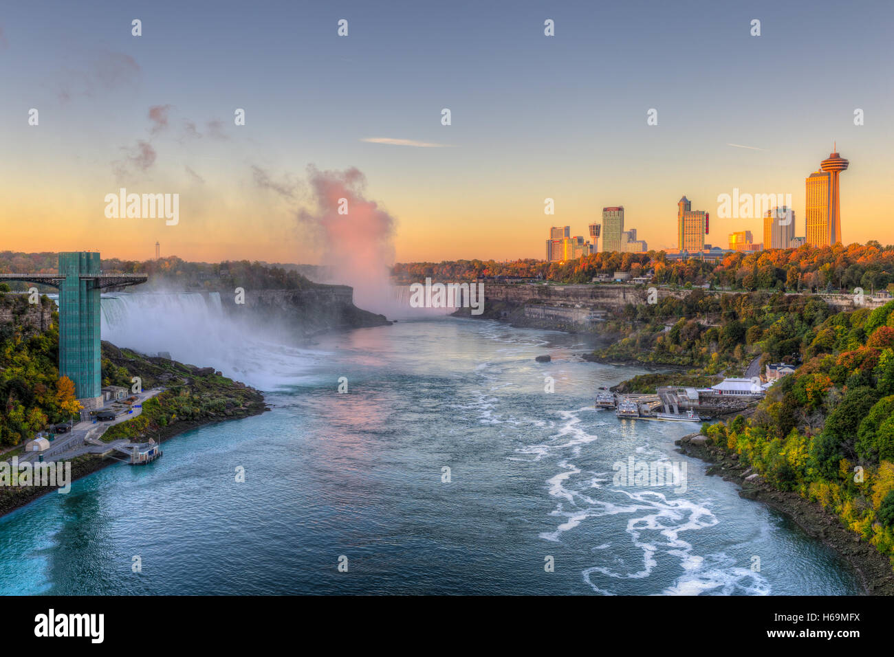 Der Niagara River, darunter die American Falls, die Horseshoe Falls und die Skyline von Niagara Falls, Ontario kurz nach Sonnenaufgang. Stockfoto