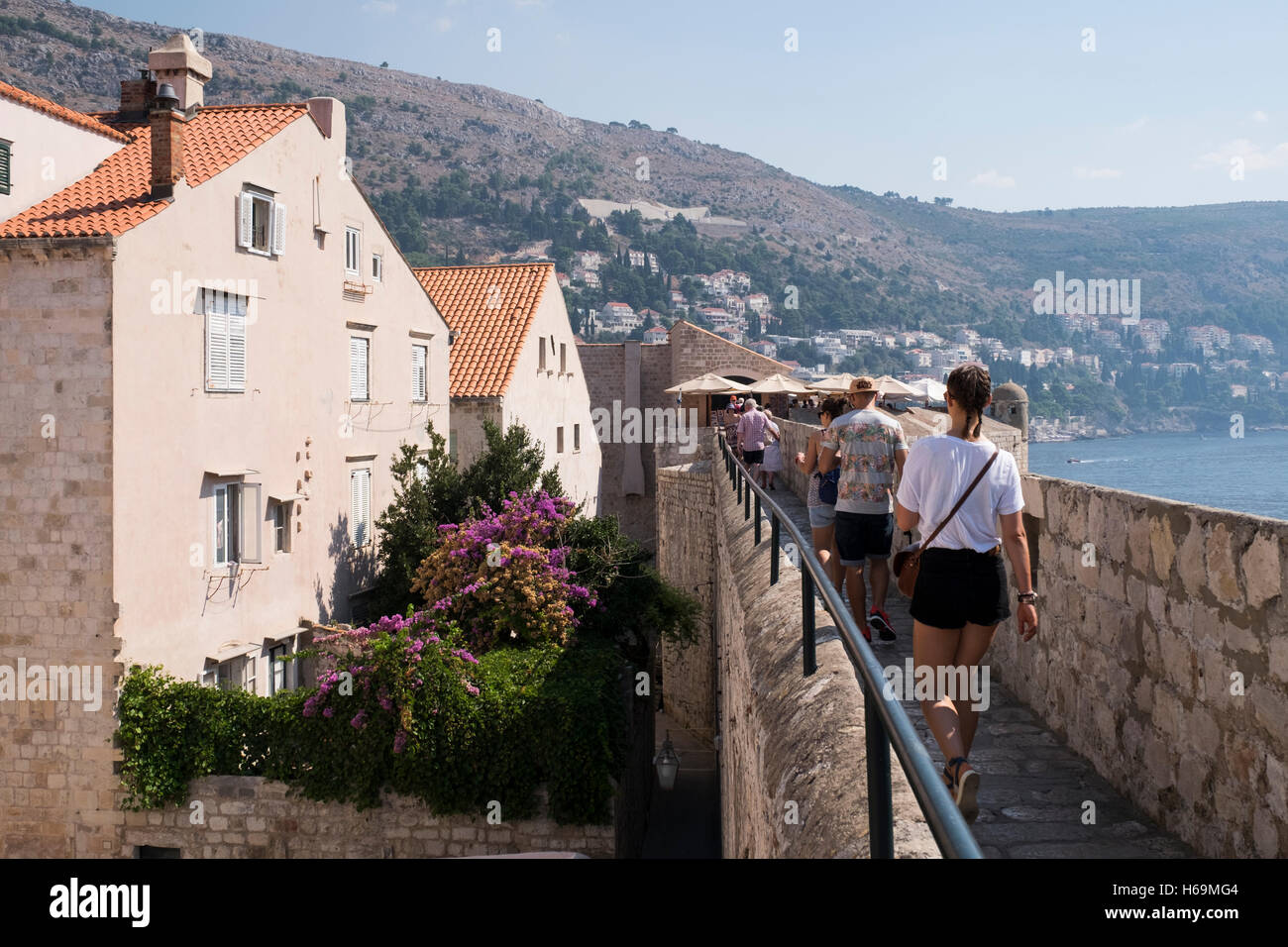 Die Menschen gehen entlang der alten Stadtmauer in Dubrovnik, Kroatien. Das UNESCO-Weltkulturerbe der Altstadt von Dubrovnik ist bekannt Stockfoto