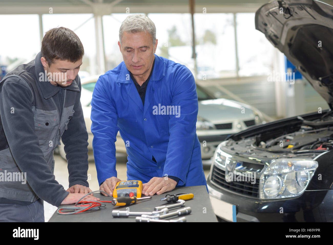 Schüler mit Lehrer, die Reparatur eines Autos während der Lehrzeit Stockfoto