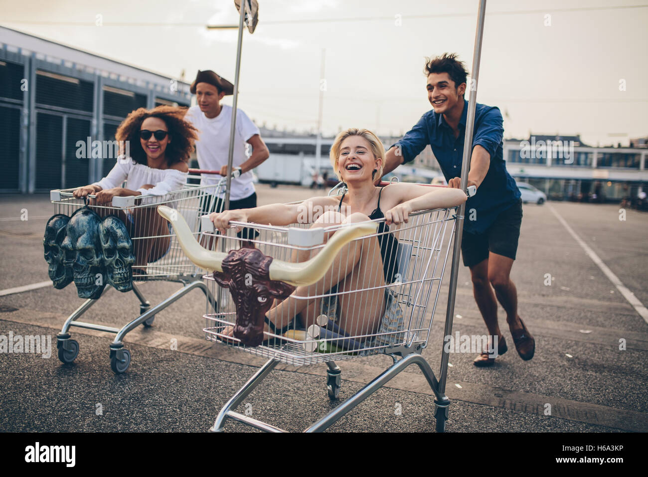 Junge Leute Rennen mit Einkaufswagen unterwegs. Gemischtrassigen Gruppe befreundeter racing mit Warenkorb. Stockfoto