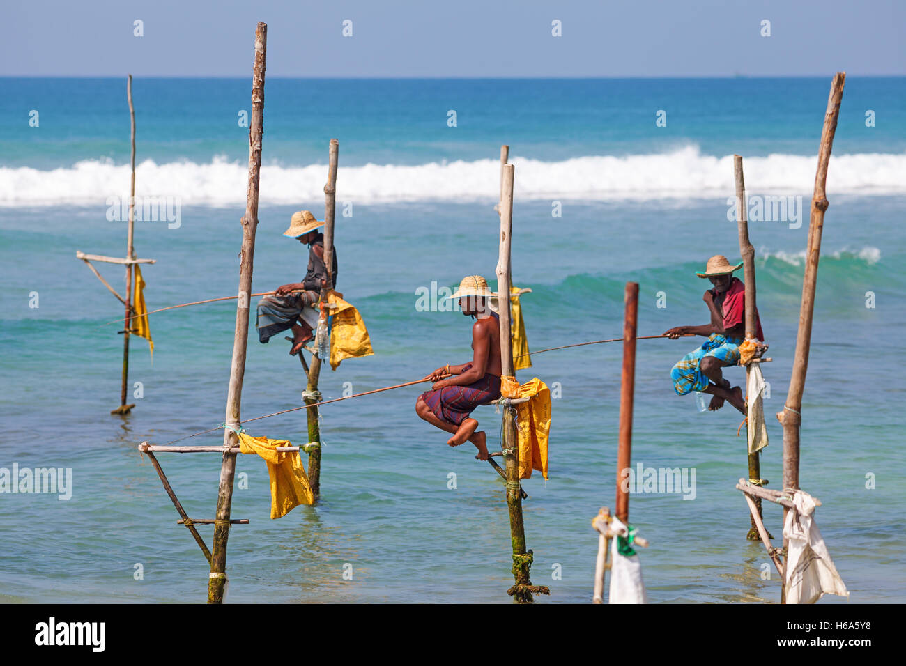 Fischer sitzen auf ihren Stelzen warten Fischschwarm, die ihre Stelzen im seichten Wasser passieren Sril Lanka Stockfoto