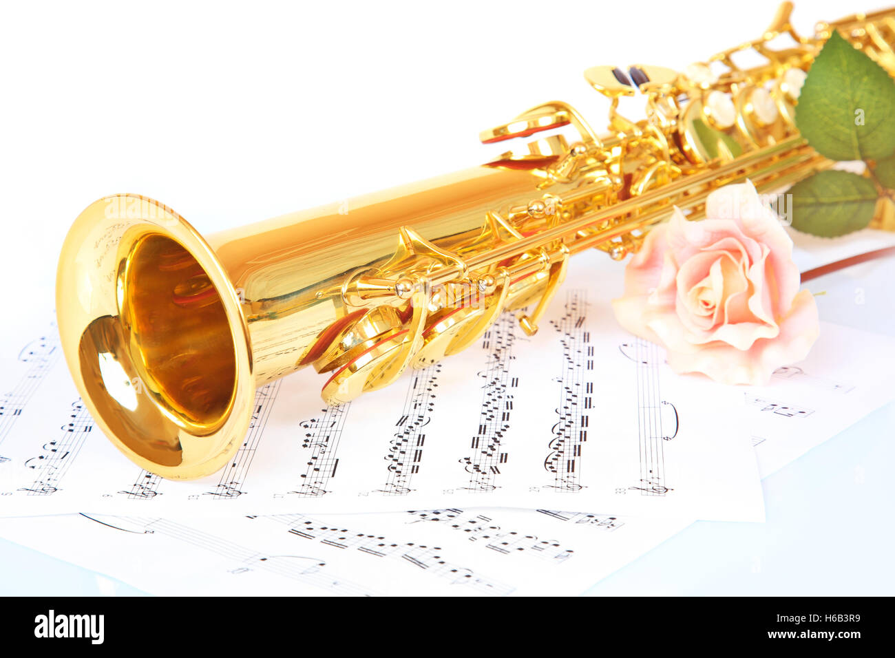 Rosa Rose, Saxophon und Musik Blatt auf weißem Hintergrund Stockfoto