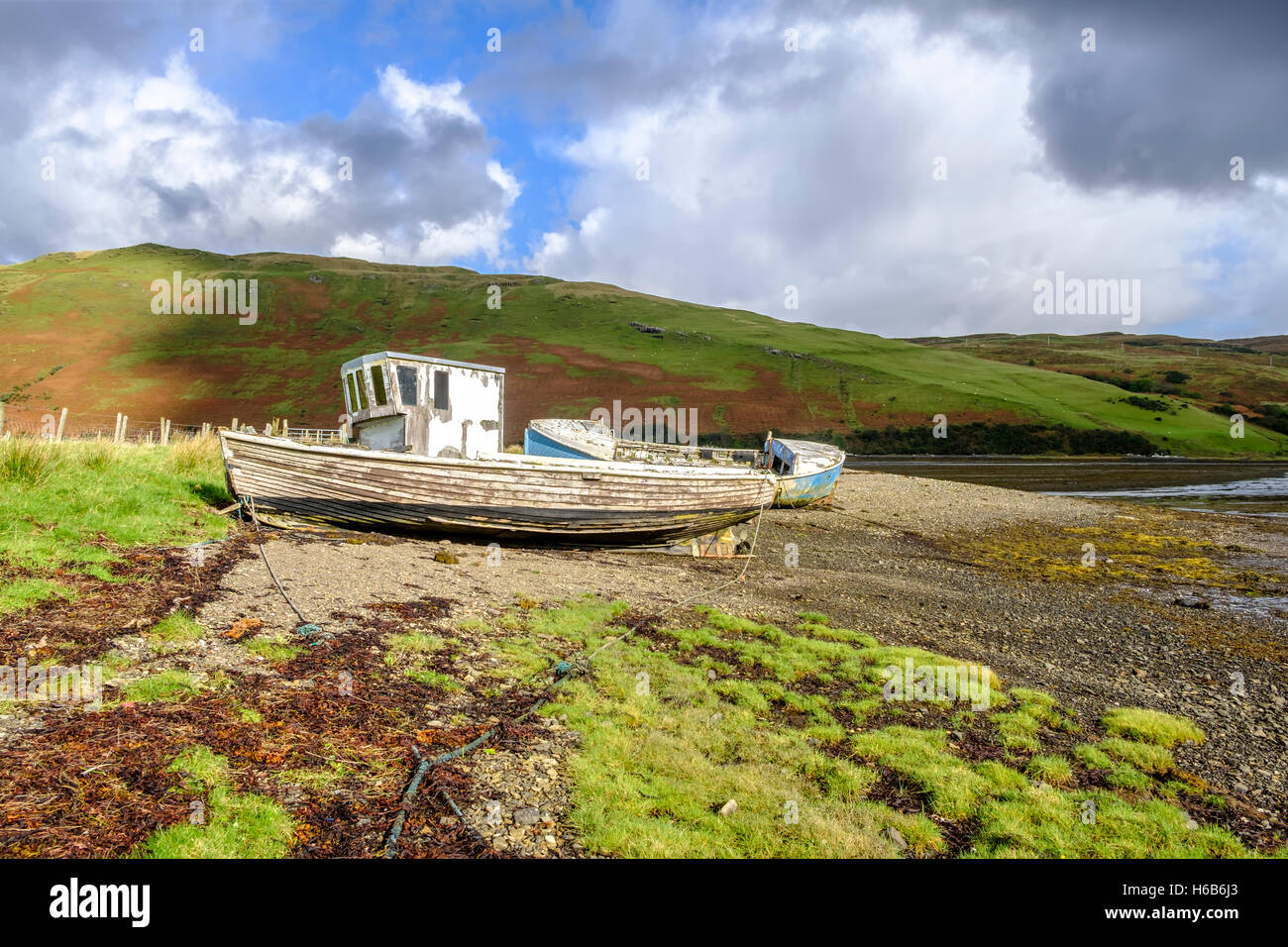 Sonne scheint auf die abblätternde Farbe von zwei alten verlassenen Holzboot Wracks am Ufer des Loch Harport auf Isle Of Skye, Schottland Stockfoto