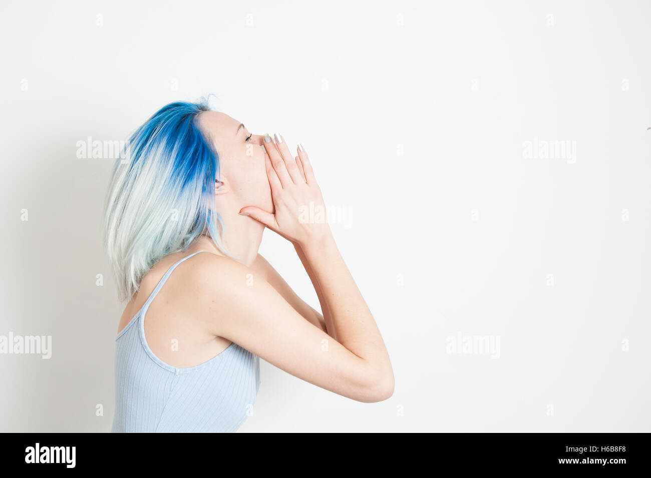 Junge Teen Frau im Hochformat von Seite, mit Weinen zu öffnen auf Mund und Hände herum, weißer Hintergrund Stockfoto