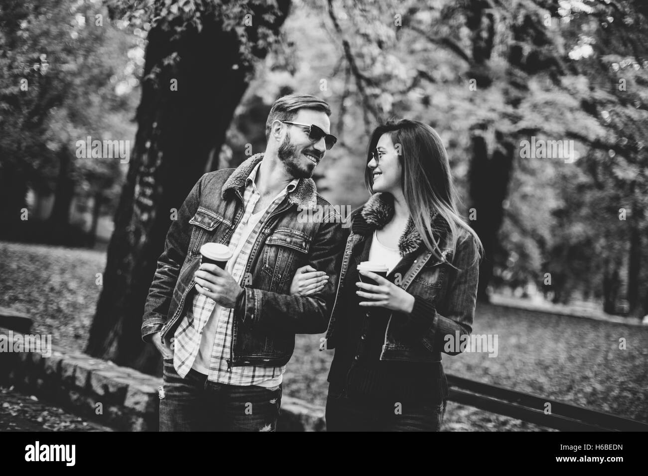 Junge Paare, die mit Kaffee zum mitnehmen im Herbst park Stockfoto