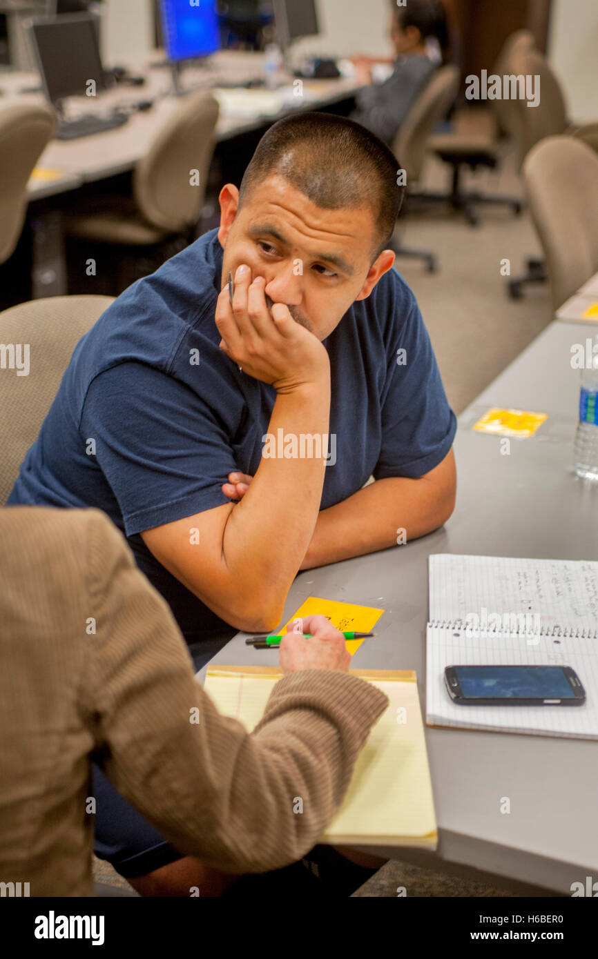 Einen mittleren Alters Hispanic Mann konzentriert sich auf Weisung des Lehrers im Learning Center ein Santa Ana, CA, Volkshochschule. Stockfoto