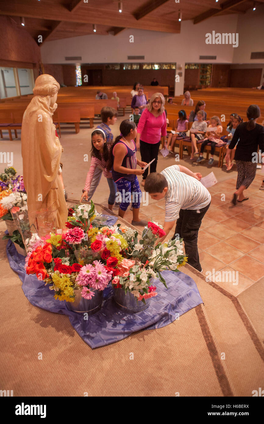 Eine Prozession von Kindern legen Sie Blumen neben einer Statue der Jungfrau Maria während der Zeremonie der Krönung Mariens am St. Timothy katholische Kirche, Laguna Niguel, CA. Das Ereignis bezieht sich auf spezielle Marienandachten gehalten in der katholischen Kirche während der m Stockfoto