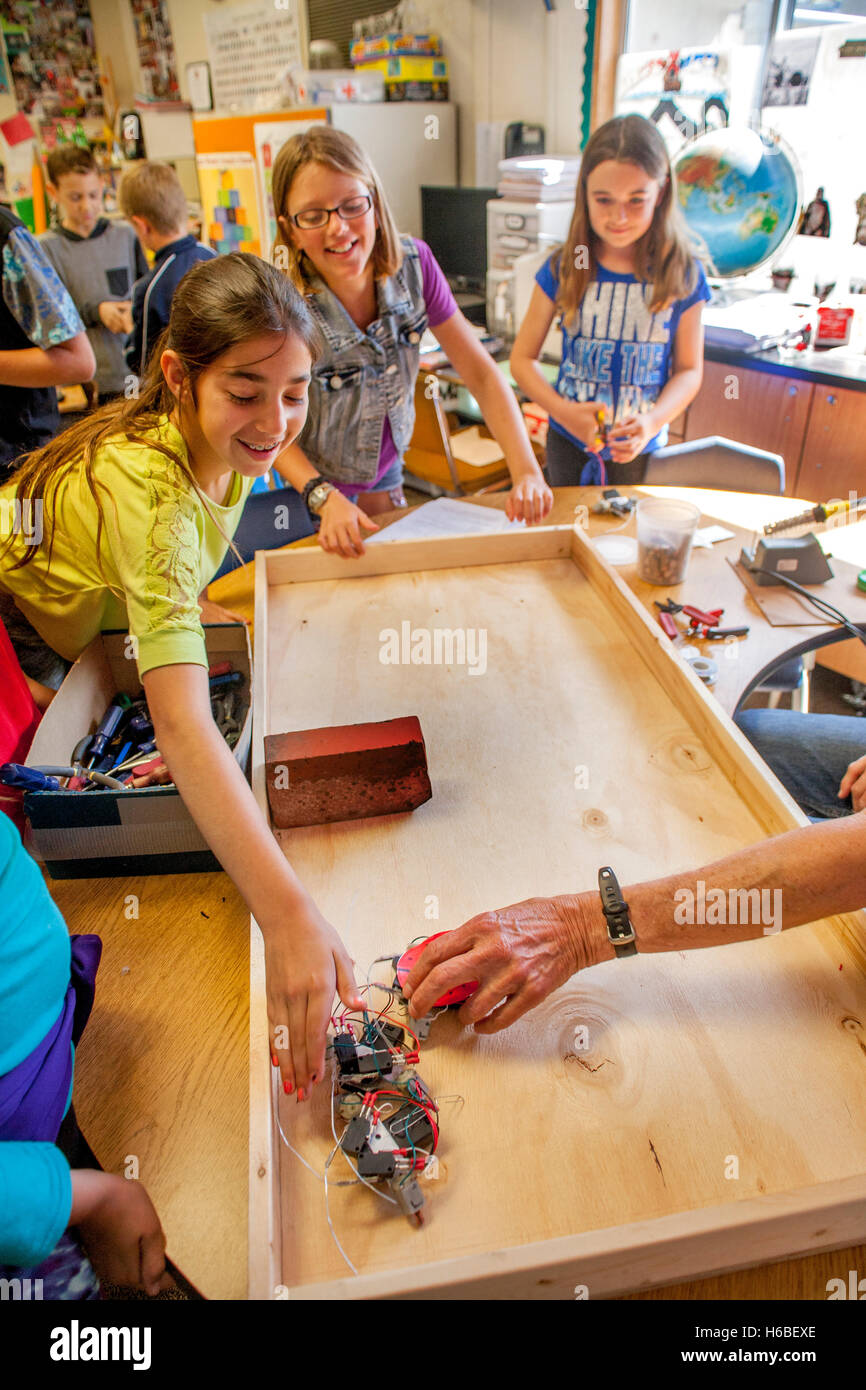 Begeisterte multirassische Grundschüler in Mission Viejo, Kalifornien, zeigen Klasse-Projekt Roboter auf einer Tischplatte. Stockfoto