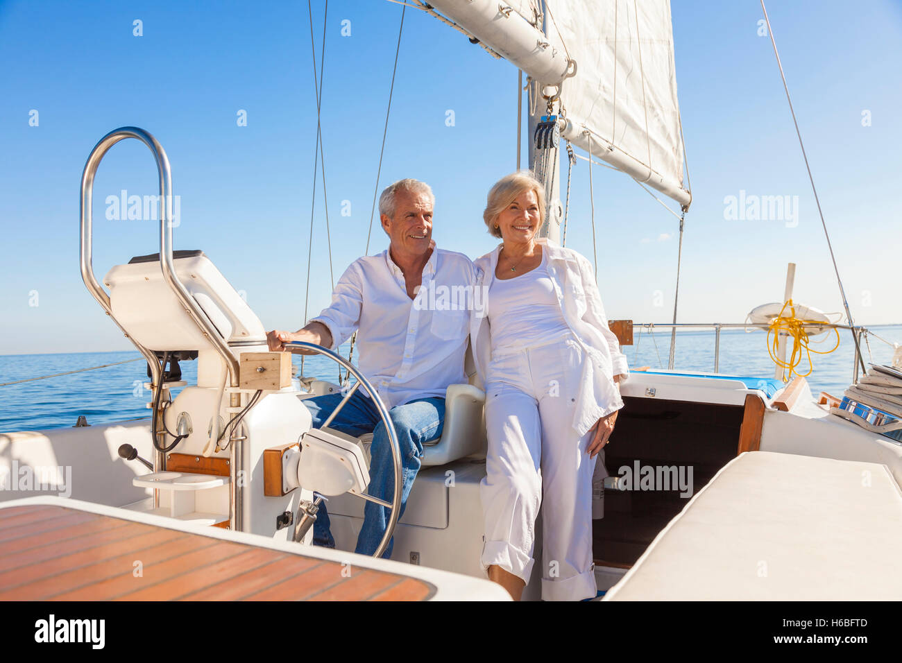 Ein glückliches senior paar lachen, haben Spaß am Steuer eine Yacht oder ein Segel Boot auf einem ruhigen blauen Meer segeln Stockfoto
