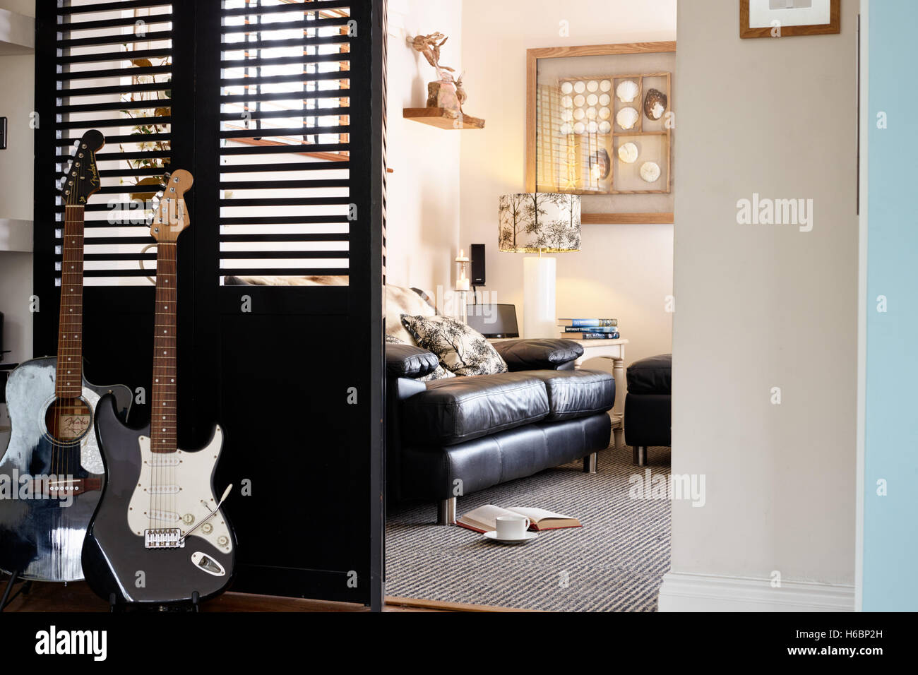 Ein Blick durch die Türen, vorbei an zwei Gitarren in einer Szene entspannt Wohnzimmer geteilt. UK Stockfoto