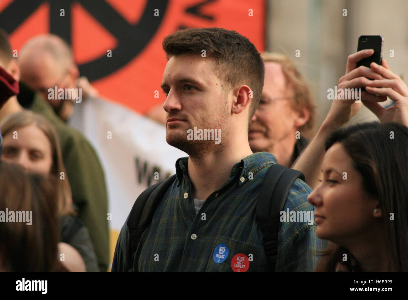 Ein Demonstrant gegen die Erneuerung des Großbritanniens Kernwaffen Systems Trident, hört Musik und reden bei der "Party und Protest" von Gruppen wie der CND starten und stoppen der Kriegskoalition außerhalb des Verteidigungsministeriums. Stockfoto