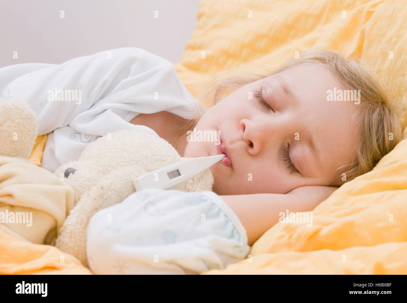 Krankes Mädchen mit Fieberthermometer im Bett Stockfoto