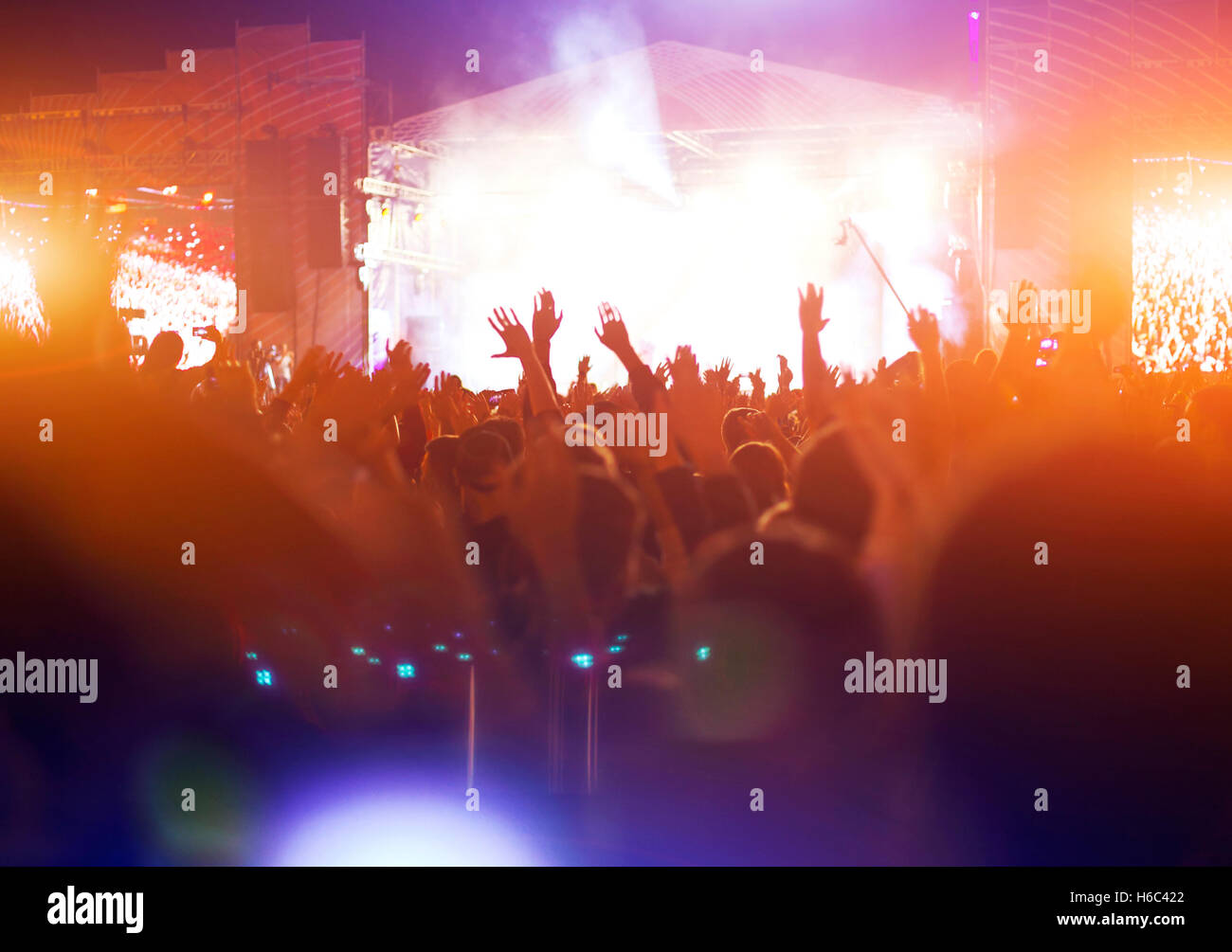 Silhouetten von Konzert drängen sich vor hellen Bühnenbeleuchtung. Nachtaufnahme Stockfoto