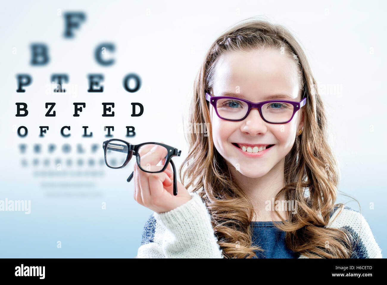 Porträt des jungen Mädchens halten Gläser mit Test-Chart im Hintergrund schließen. Stockfoto