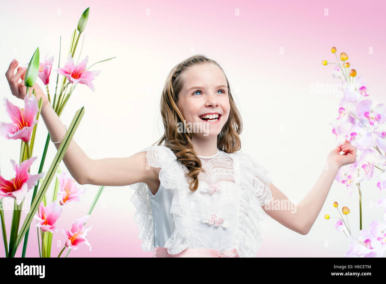 Porträt der glückliche junge Kommunion Mädchen unter Blumen hautnah. Stockfoto