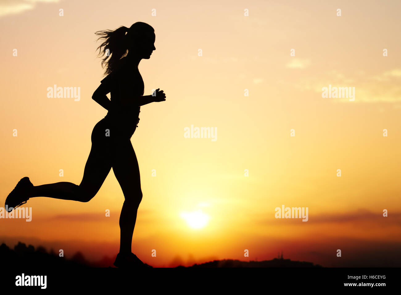 Aktion Silhouette des weiblichen Jogger bei Sonnenuntergang hautnah. Mädchen wieder gegen intensiven orangefarbenen Himmel beleuchtet. Stockfoto