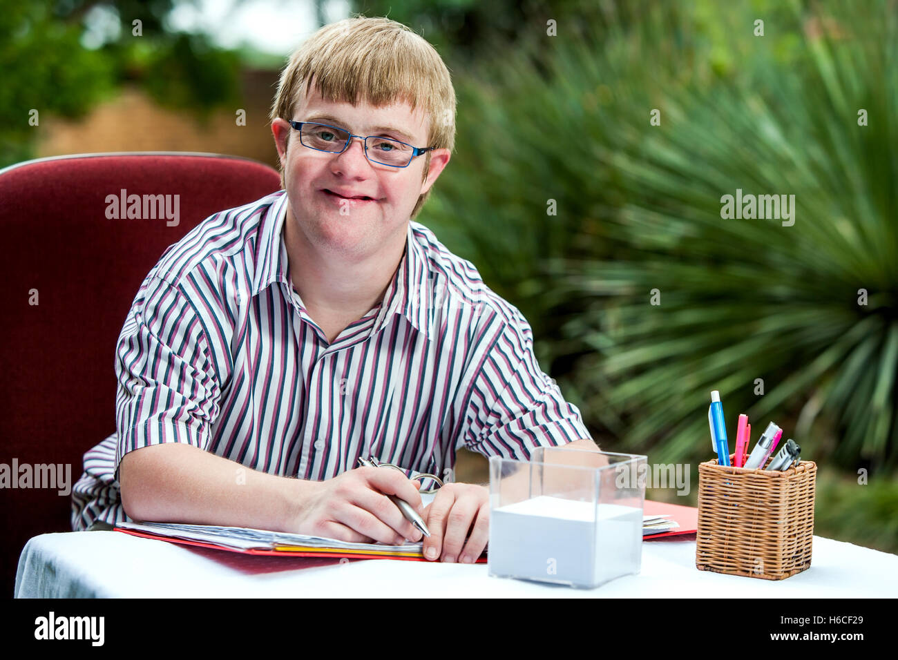 Porträt von behinderten Schüler mit Brille am Schalter im Garten hautnah. Stockfoto