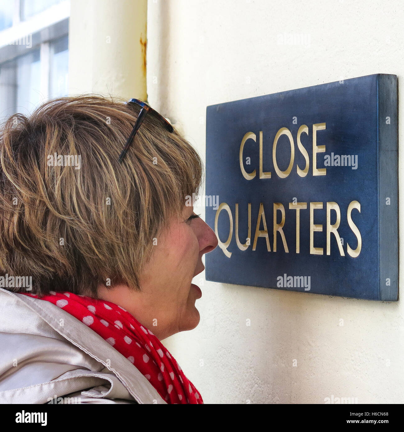 Frau mit Kurzsichtigkeit sehr genau beobachten' Close Quarters' Haus Name für humorvollen Effekt. Stockfoto