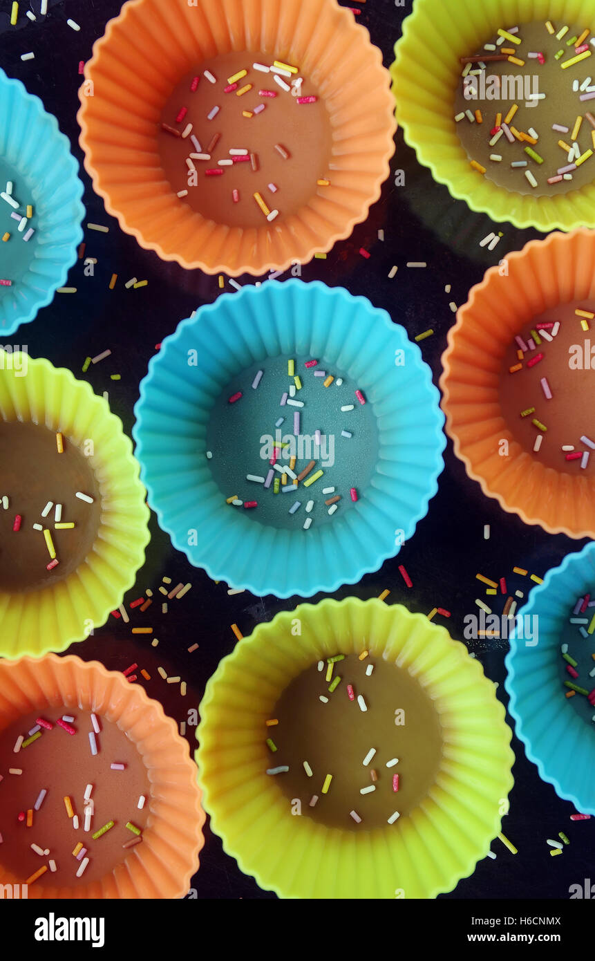 Draufsicht auf eine Gruppe von bunten Silikon Cupcake Formen auf dunklem Hintergrund Stockfoto