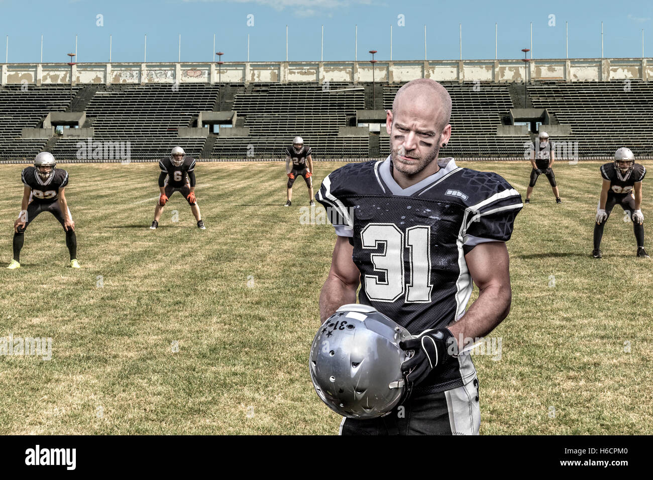 Porträt von ein ernst aussehende american-Football-Spieler, der in einem desolaten Stadion steht. Stockfoto