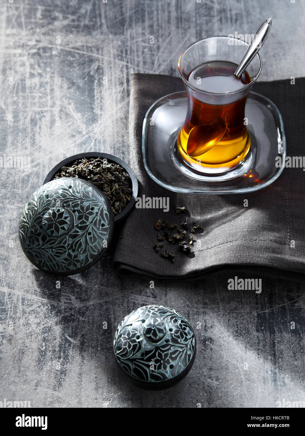 Tee im Glas grau Serviette, Oolong-Tee, heißes Getränk neben kleine Dose mit Tee gefüllt Stockfoto