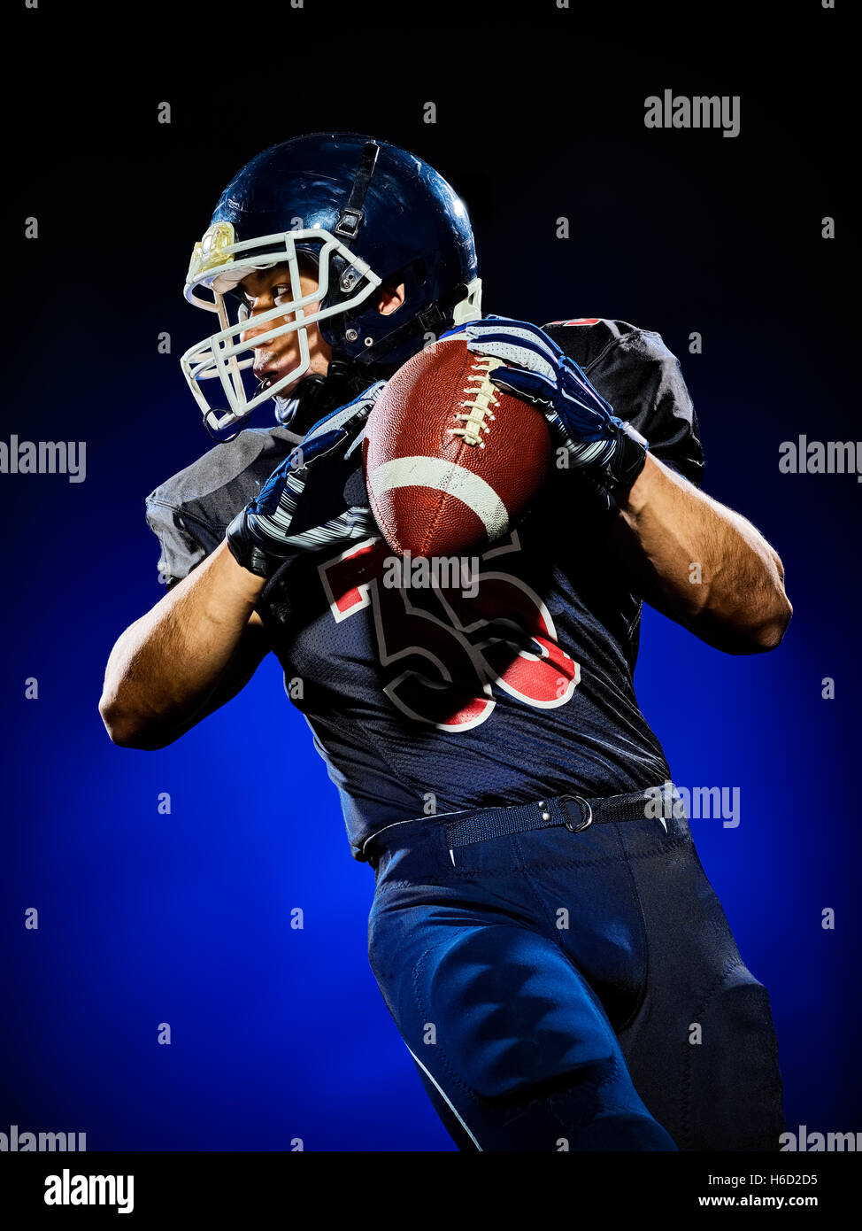 US-amerikanischer american-Football-Spieler Einmann auf bunten schwarzem Hintergrund isoliert Stockfoto
