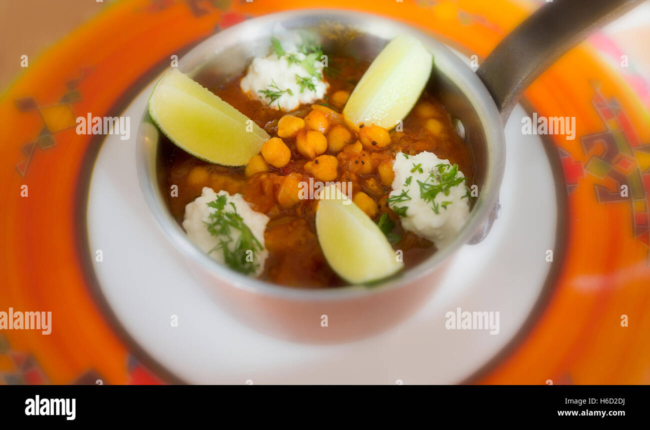 Kichererbsen Curry mit Kurkuma und Tomaten mit Kalk und Joghurt serviert in einem Kupfer pan Stockfoto