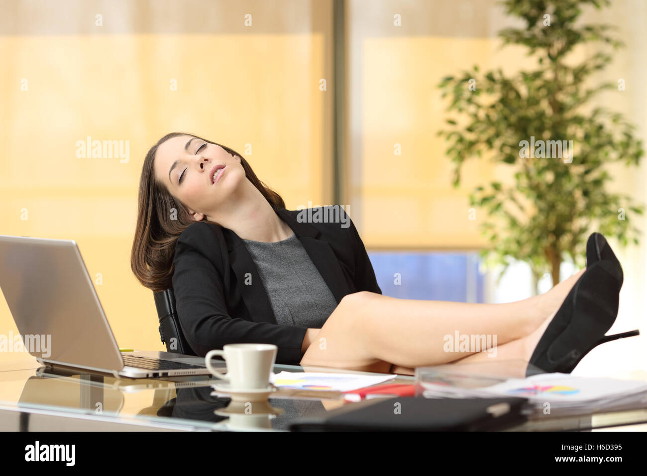 Faul oder müde Geschäftsfrau schlafen bei der Arbeit mit den Beinen über den Tisch im Büro