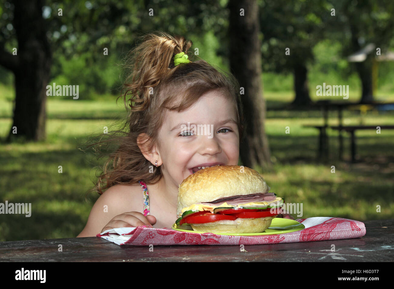 hungriges kleine Mädchen große Sandwich Essen im park Stockfoto