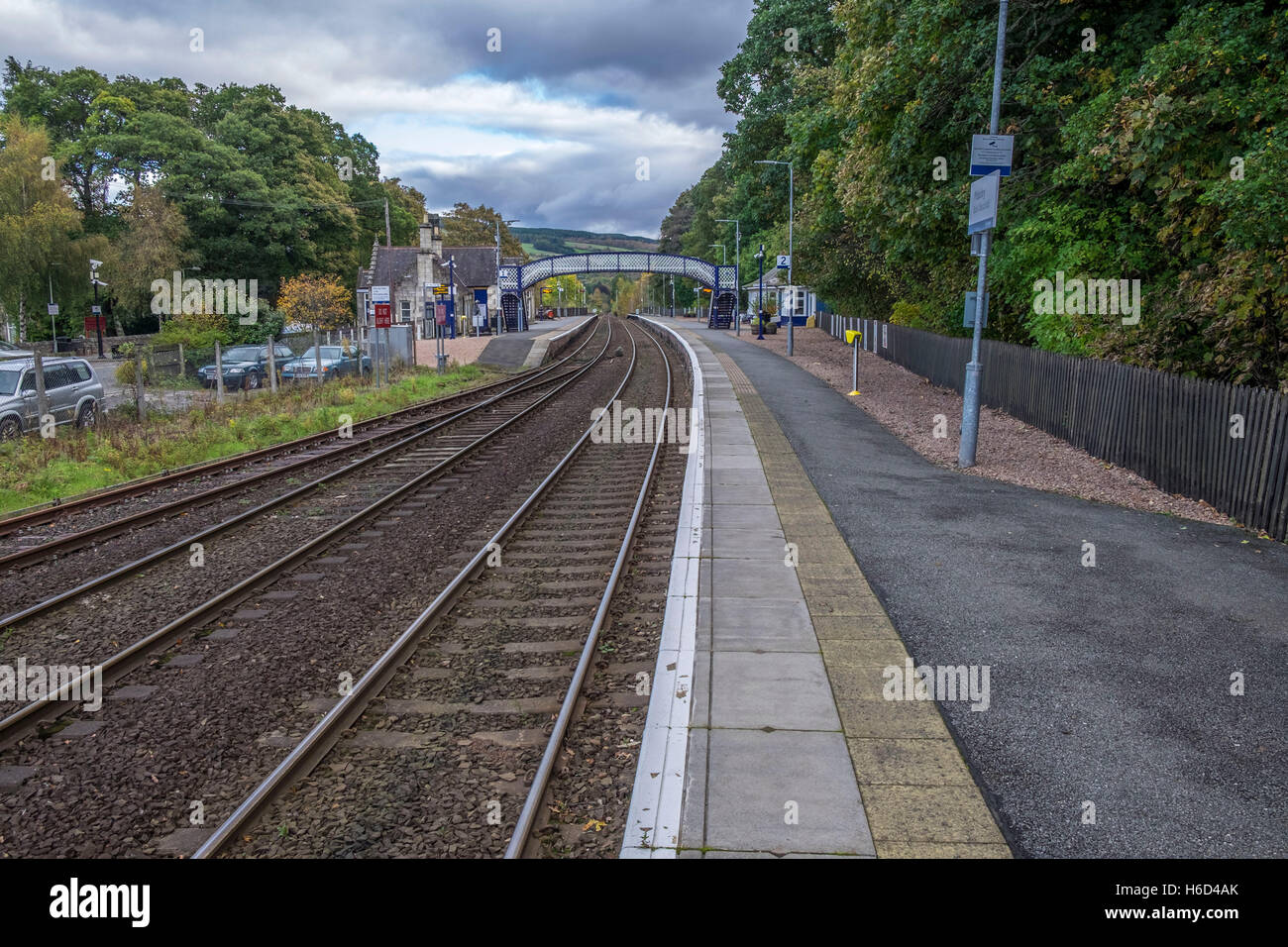 Die Eisenbahnlinien und Plattform in Pitlochry Station mit einem Steg in der Ferne. Stockfoto