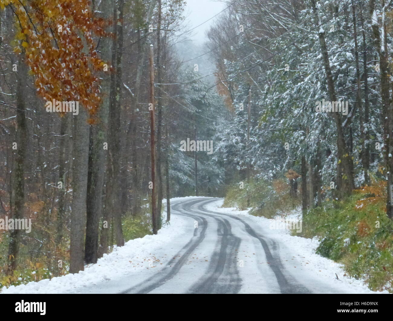 Kurvenreiche Straße im Winter mit Reifenspuren im Schnee Stockfoto