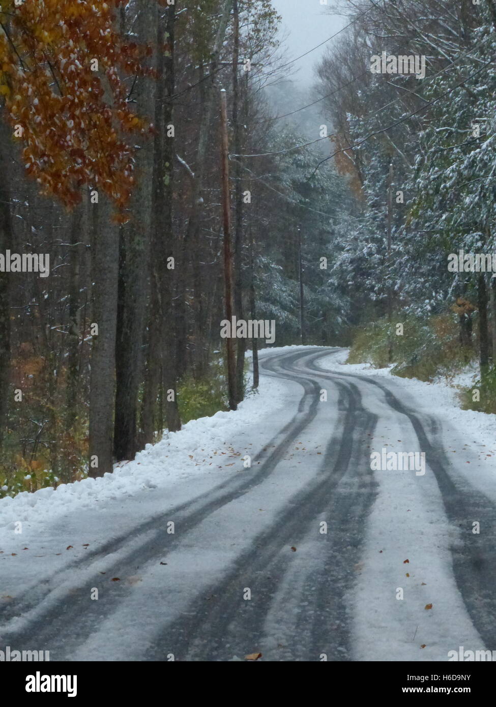 Kurvenreiche Straße im Winter mit Reifenspuren im Schnee Stockfoto