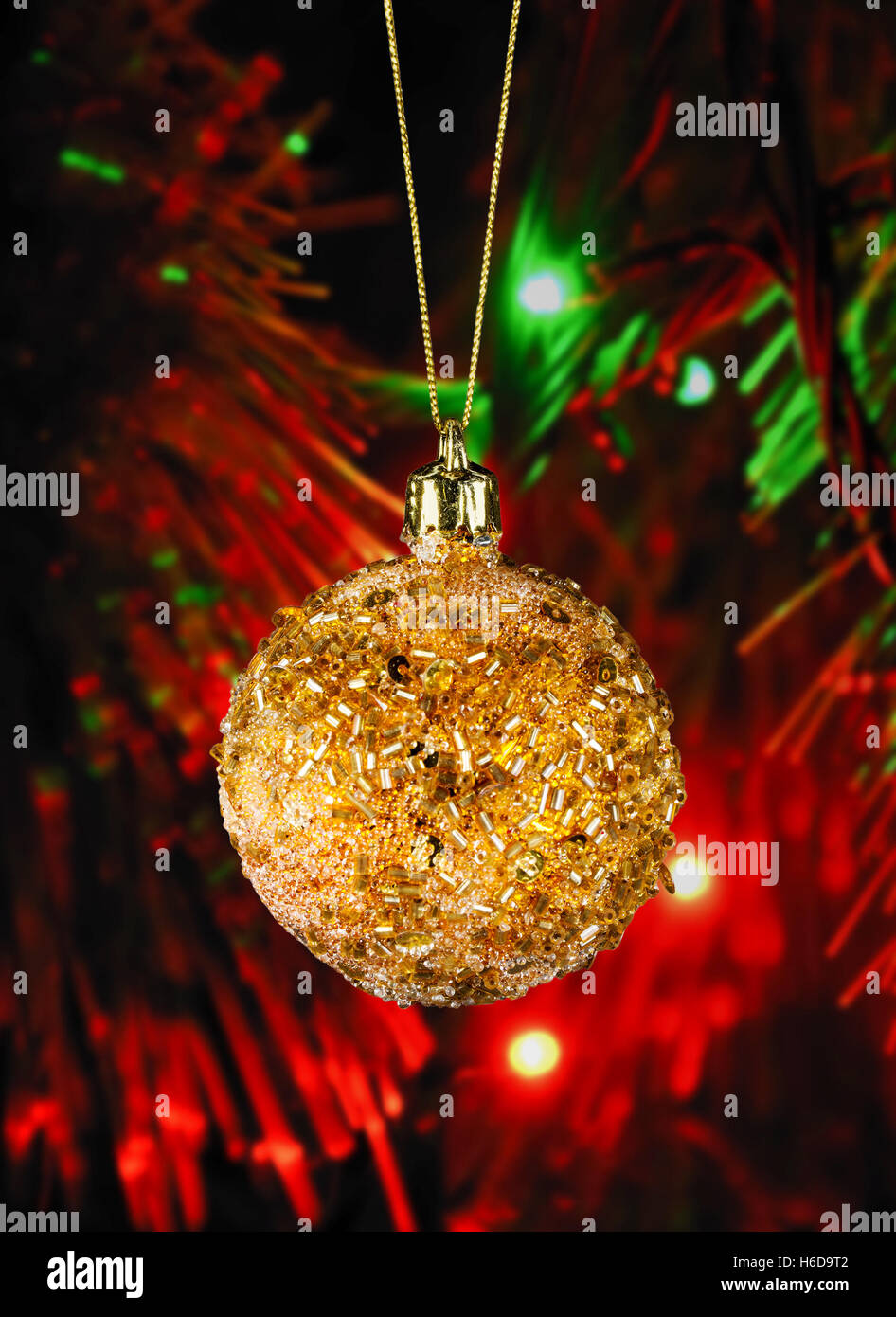 Goldene Weihnachtskugel im defokussierten Hintergrund unscharf Weihnachtsbeleuchtung in der Nacht Stockfoto