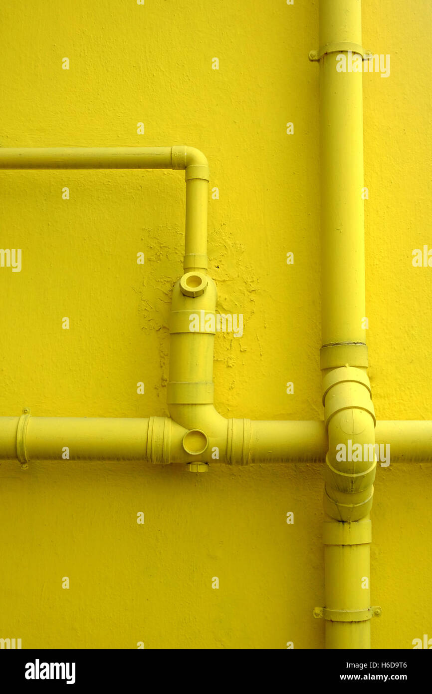 Gelbe Wand von Gebäude- und Wasserleitungen Stockfoto