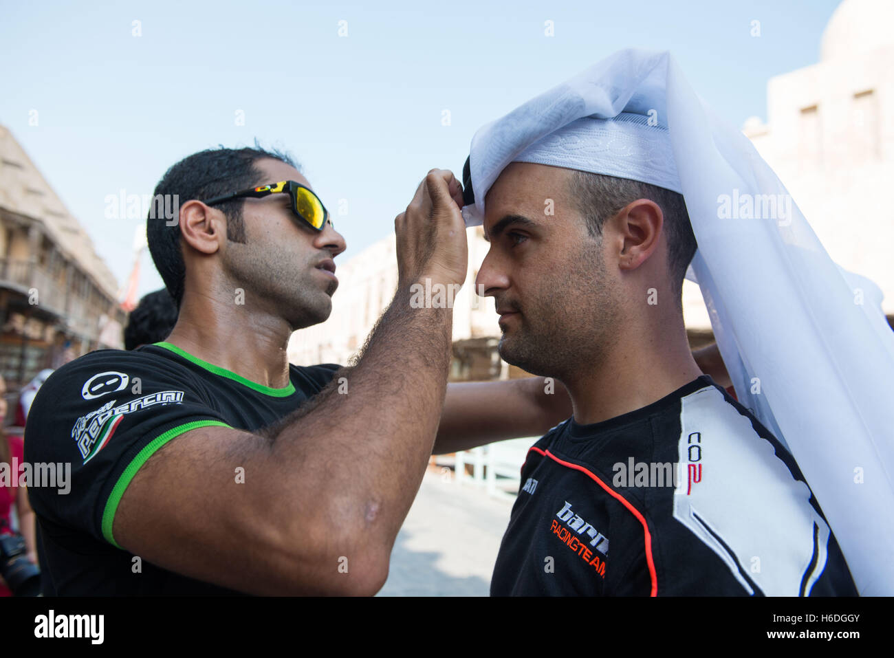 Souq Waqif Doha, Qatar. 27. Oktober 2016. Saeed Al Sulati Adjustes der Kopfschmuck von Xavi Fores während eines Besuchs in Souq Waqif in Doha Credit: Tom Morgan/Alamy Live News Stockfoto
