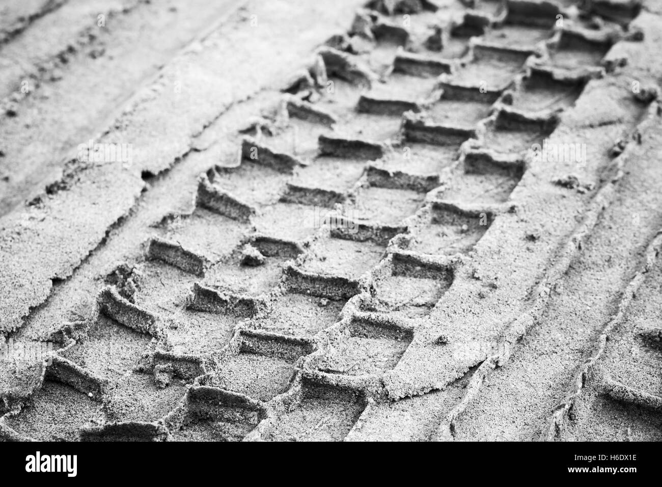 Reifen-Track auf grauer Sandboden, abstrakte monochrome Transport Hintergrundfoto mit selektiven Fokus Stockfoto