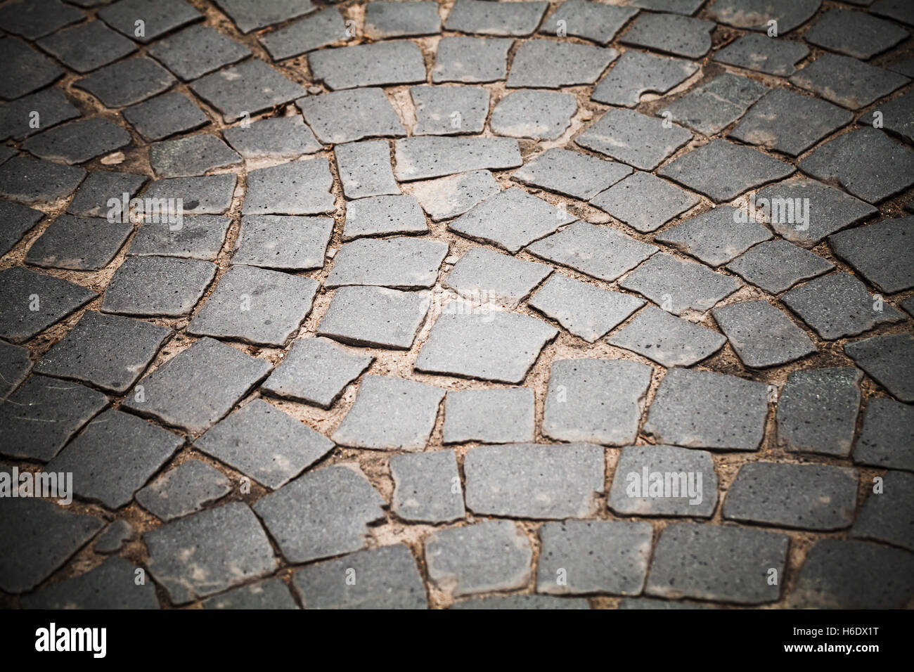 Dunkel grau gepflasterten Straße, Stein Straßenpflaster, Hintergrundfoto mit selektiven Fokus und Vignette-Effekt Stockfoto