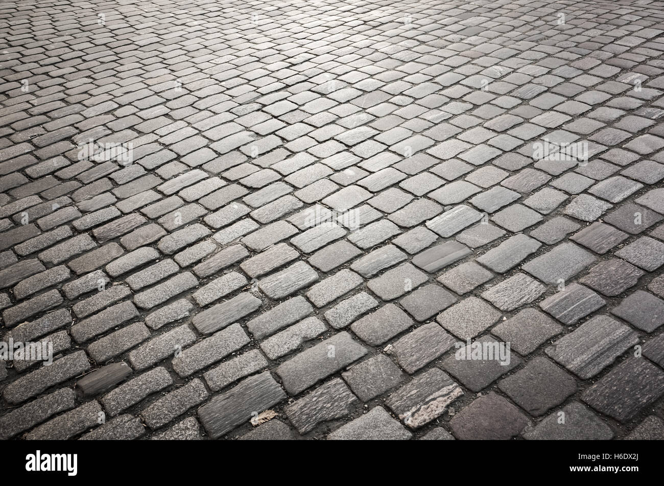 Dunkel grau gepflasterten Straße, Stein Straßenpflaster, Hintergrundfoto mit selektiven Fokus Stockfoto