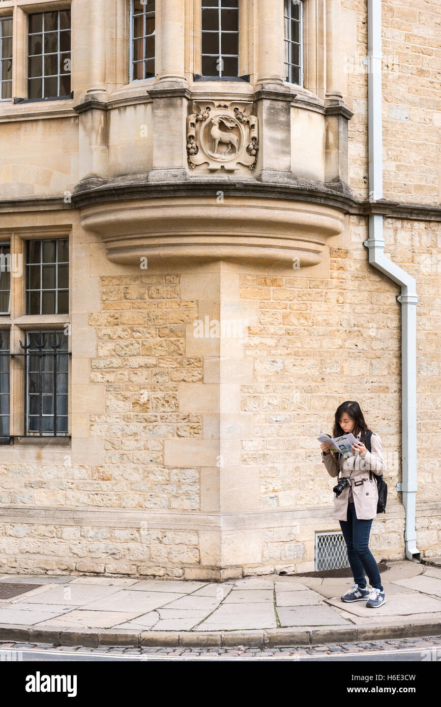 Asiatin liest einen Reiseführer auf der 'Catte Street' in Oxford, Oxfordshire, Großbritannien Stockfoto