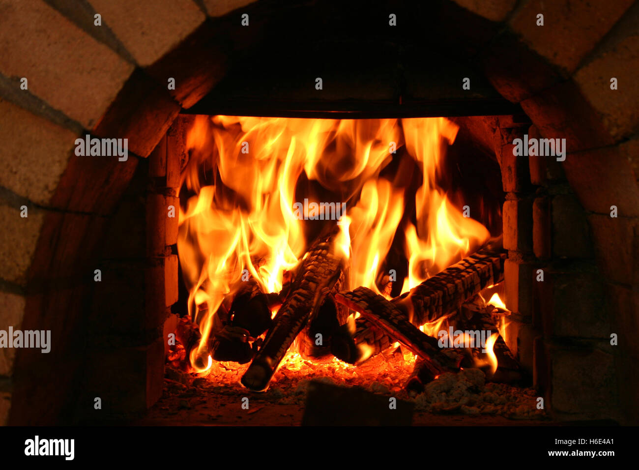 Brennende Maschinenbordbücher in traditionellen Steinofen in Landhausküche Stockfoto