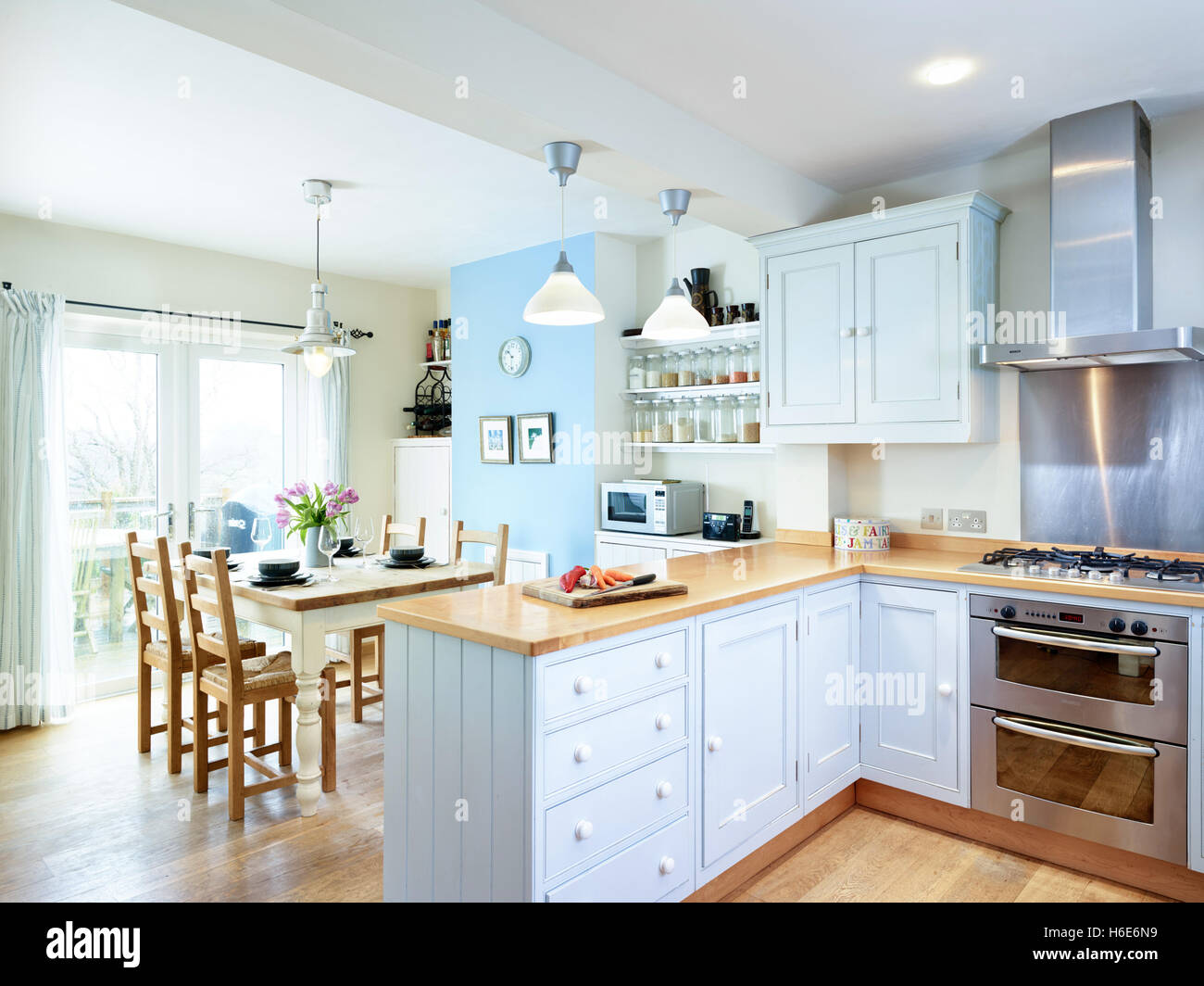 Eine moderne, offene Küche zum Abendessen mit integriertem Backofen, Herd, Haube & Holz Arbeitsflächen. Gloucestershire, Vereinigtes Königreich Stockfoto