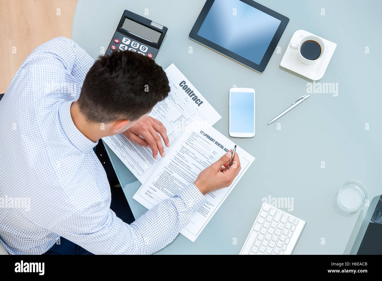 Porträt des jungen Büroangestellten Vertragsunterlagen ausfüllen hautnah. Draufsicht der junge Mann am Tisch mit Stift und Dokumente. Stockfoto