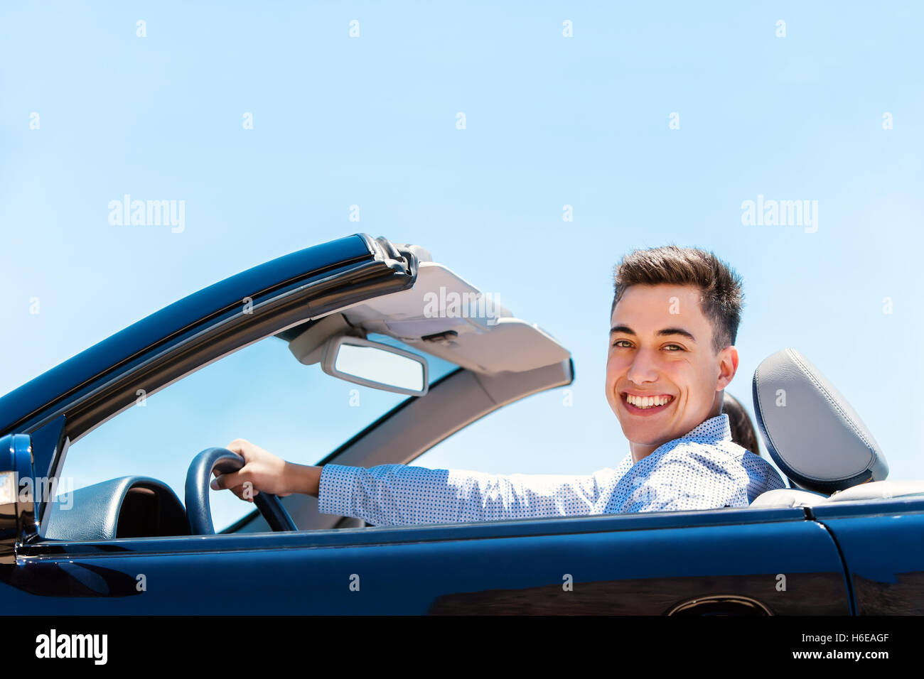 Porträt von hübscher junger lächelnder Mann luxuriöse blaue Cabrio fahren. Stockfoto